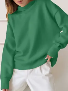 Detail view of cozy green long-sleeve oversized sweatshirt worn with white pants, casual style.