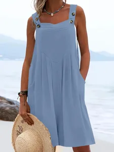 Close-up detail of blue overall jumpsuit with buttons and pockets for summer beach wear.