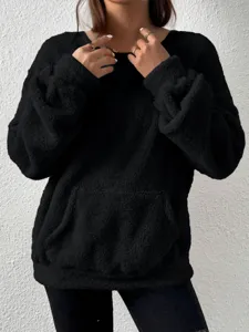 Close-up detail of black fluffy sherpa pullover hoodie with cozy fabric and pocket design.