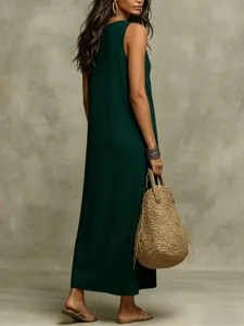 Detailed shot of a stylish dark green sleeveless maxi dress, worn by a model with straw bag.