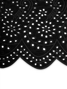 Détail de tissu brodé noir ajouré, belle broderie anglaise et ourlet festonné gros plan.