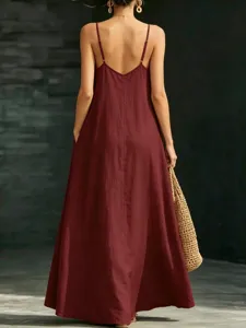Back view detail of an elegant burgundy spaghetti strap maxi dress with flowing hem and pockets.