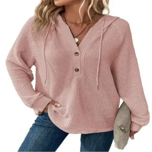 Dettaglio in primo piano della felpa rosa in maglia waffle con scollo a V e bottoni.