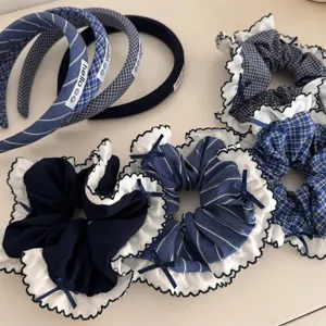 Detailed view of blue plaid and solid hair scrunchies with white lace trim and bows.