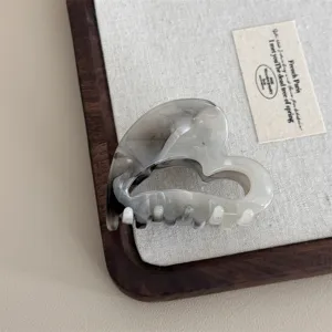 Close up detail of the ink wash black and grey heart shaped hair claw clip texture.