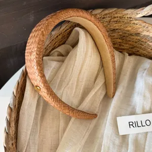 Elegant brown woven headband with delicate gold metal button detail, chic hair accessory.