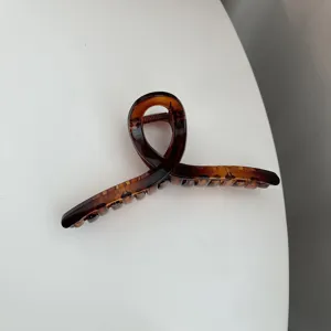 Detail shot of the elegant tortoiseshell hair claw clip featuring a unique cross design.