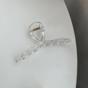 Transparent minimalist hair claw clip detail shot, showing clear resin texture and spring.