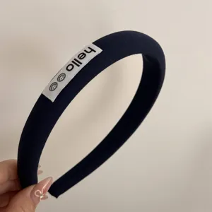 Detail shot of navy blue fabric headband with cute hello text label, simple and stylish.