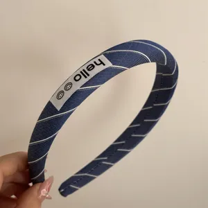 Navy blue striped fabric headband with cute hello label detail, stylish hair accessory for women.