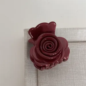 Gros plan détaillé d'une pince à cheveux rose rouge foncé, design floral pour coiffure demi-queue.