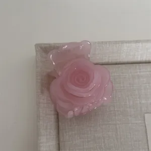 Gros plan détaillé d'une pince à cheveux rose en forme de rose pour coiffures élégantes.