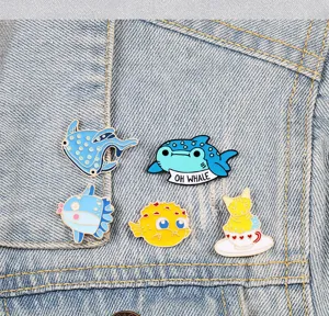 Süße Meerestiere Emailliernadeln Detail, zeigt Walhai und Kugelfisch Design auf Jeans.