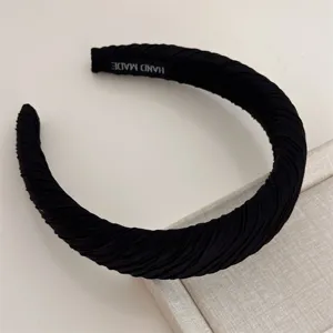 Detail shot of the black pleated fabric wide headband, showing fine hand-made texture and details.