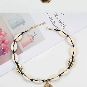 Dettaglio collana conchiglie intrecciata boho, ciondolo conchiglia naturale dorata.