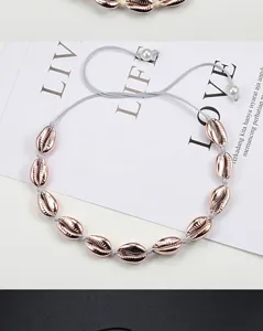 Close-up of rose gold plated cowrie shell necklace with adjustable cord and pearl accents.