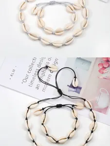 Détail des superbes parures de colliers et bracelets en coquillages cauris tressés.