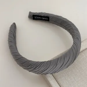 Detailed shot of grey pleated fabric headband, handmade style daily hair accessory for women.