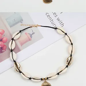 Collana girocollo bohémien fatta a mano in conchiglia di ciprea naturale con cordino nero e ciondolo.