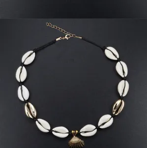 Primo piano di una collana girocollo boho in conchiglie intrecciate a mano con ciondolo dorato.