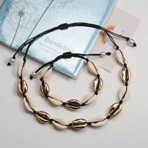 Set bracciale collana cordino intrecciato con conchiglie di cauri dorate e perle boho.