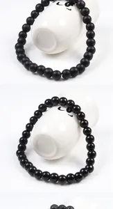 Black beaded bracelet detail showing matte and glossy beads on ceramic display props.