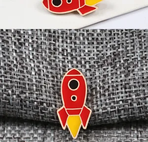 Detailed shot of the cute red rocket enamel brooch, featuring bright yellow flame details.