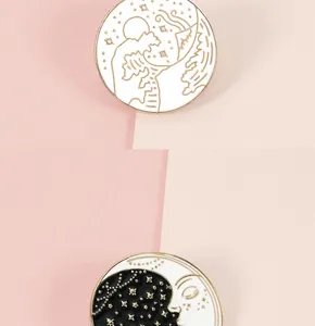 Primer plano detallado del broche de esmalte metálico blanco y negro con sol y luna.