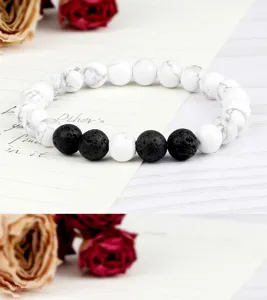 Gros plan détaillé du bracelet de perles en howlite blanche et pierre de lave noire avec texture.