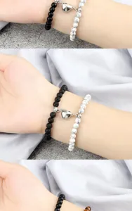 Primo piano dettagliato di bracciali di perle magnetiche di coppia con chiusura a cuore polso.