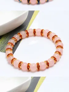 Primo piano dettagliato di un bracciale con perle di cristallo rosa e strass dorati.