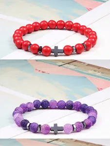 Detailopname van natuurstenen kralenarmbanden met een zwart kruisbedeltje en metalen kralen.