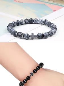 Detailopname van kralenarmband met zwart kruishanger en metalen afstandhouders stijlvol.