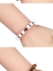 Armband detail met witte kraal, hematiet kruis bedel en tigerogen edelsteen accenten.