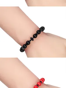 Vulkanische steen kruis armband details met matte zwarte kralen en rode kralen op de pols.