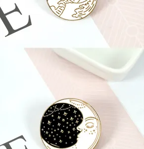 Primer plano detallado de broches de esmalte en blanco y negro con diseños de luna y olas.
