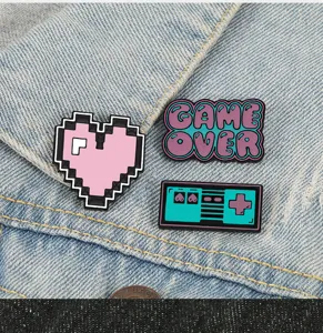 Primer plano detallado de pines de esmalte retro pixel corazón y game over en mezclilla.