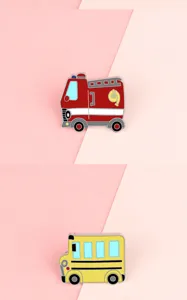 Close-up detail of cute cartoon fire truck and school bus alloy enamel pin badges.