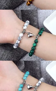 Détail de bracelet de couple avec perles en pierres précieuses et fermoir cœur magnétique.