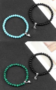 Dettaglio in primo piano di bracciali di perle magnetiche per coppie con ciondoli a cuore.