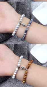 Close-up detail shot of couple magnetic stone bead bracelets worn on wrist, showing details.