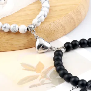 Set di bracciali di coppia magnetici con perline bianche nere e chiusura a cuore.
