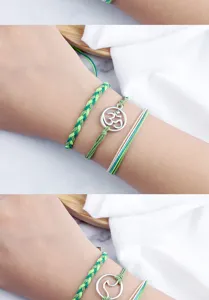 Primo piano di braccialetti dell'amicizia intrecciati a mano in verde con affascinanti ciondoli.