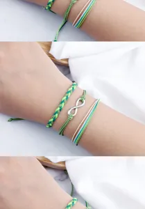Primo piano di braccialetti dell'amicizia verdi intrecciati a mano con ciondolo infinito argento.