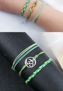 Bracciali dell'amicizia intrecciati a mano in dettaglio con cordini verdi e ciondoli in metallo.