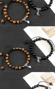 Close-up detail of handmade braided couple beaded bracelets featuring magnetic heart charm.