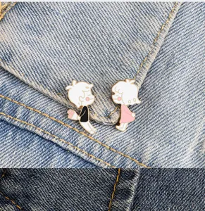 Detailed view of cute cartoon couple enamel brooches, sweet boy and girl designs for outfits.