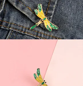 Close-up detail of a charming enameled dragonfly brooch pinned on denim and geometric background.