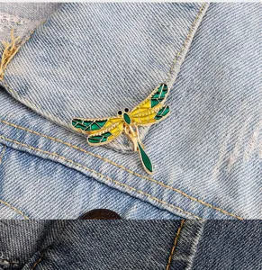 Dragonfly brooch detail shot, gold tone frame with green and yellow enamel, clothing accessory.