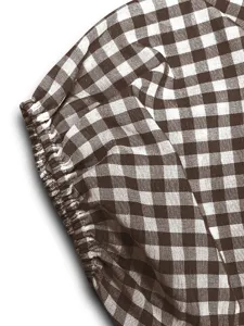 Détail de tissu à carreaux Vichy marron et blanc, poignet élastique froncé, texture douce.